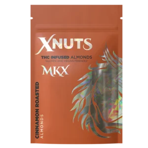 A close-up shot of a handful of shiny, cinnamon-coated roasted almonds, with a product label in the background showing the THC content and quantity.