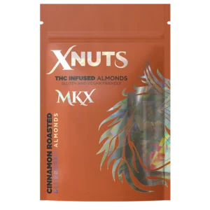 A close-up shot of a handful of shiny, blueberry and cinnamon-coated roasted almonds, with a product label in the background showing the THC content and quantity.