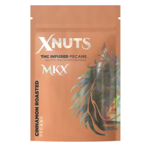 A close-up shot of a handful of shiny, cinnamon-coated roasted pecans, with a product label in the background showing the THC content and quantity.